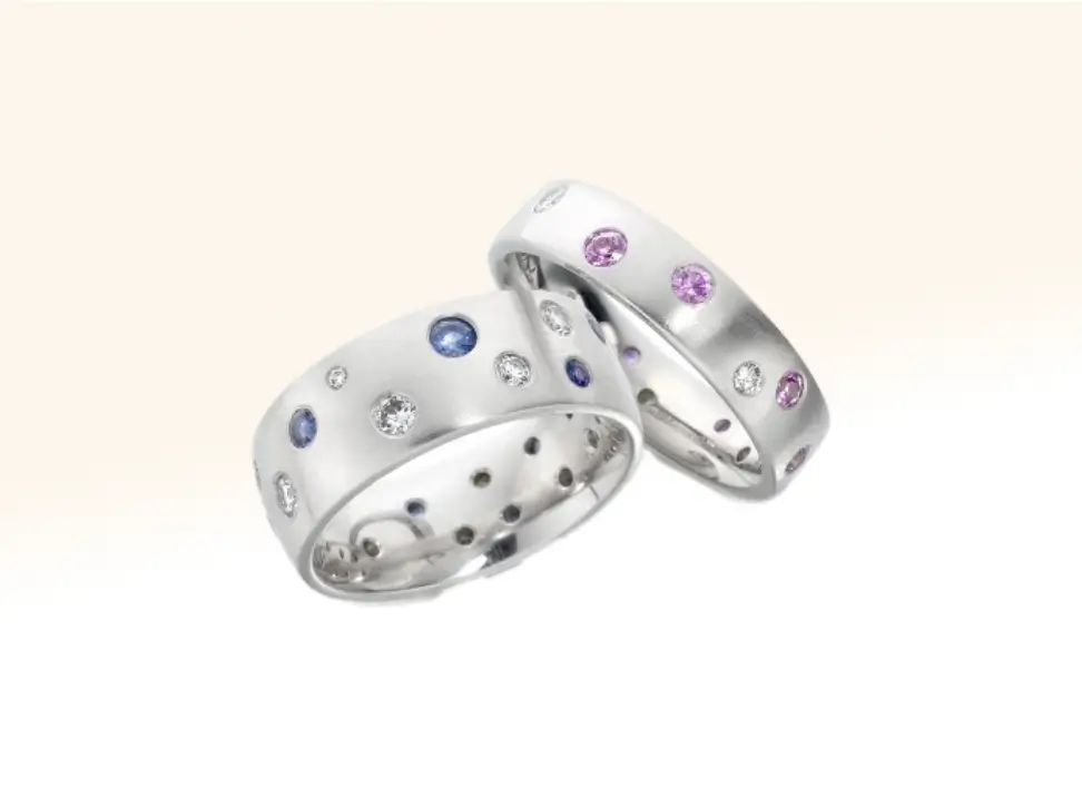 Two celebration rings for a new arrival: one featuring blue sapphires and diamonds, and the other adorned with pink sapphires and diamonds, symbolising love and joy