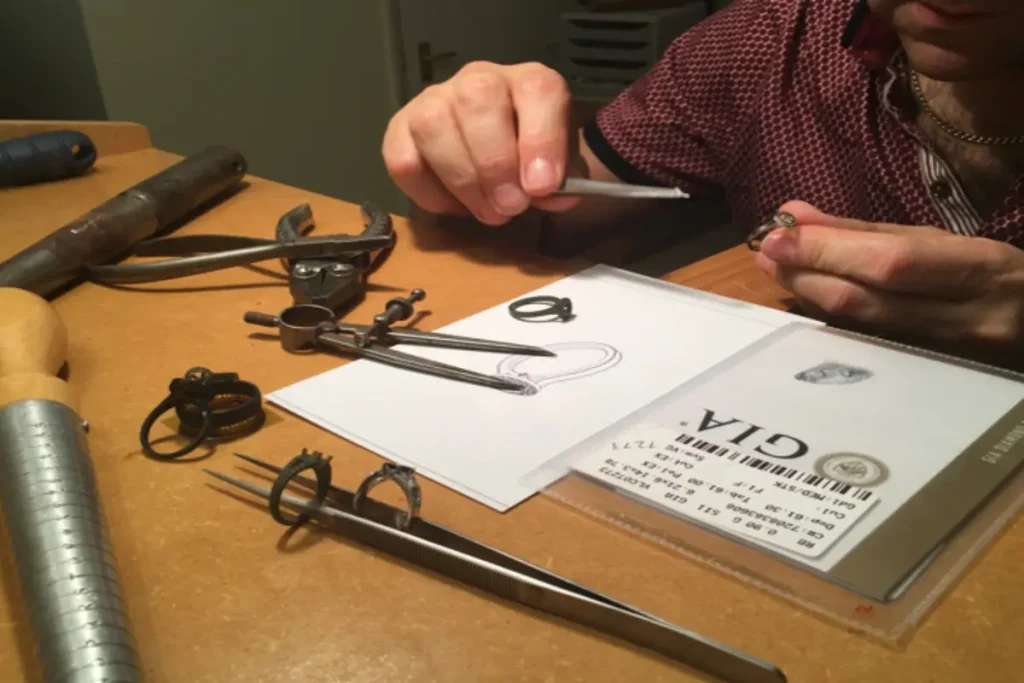 David Law at his jeweller’s bench, working on a temporary engagement ring, diamonds, and design sketches.
