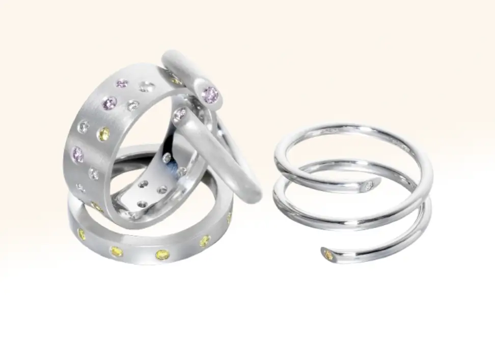 Scattered natural diamond eternity rings paired with a snake-styled eternity ring and a split ring adorned with coloured diamonds, showcasing bold and unique designs