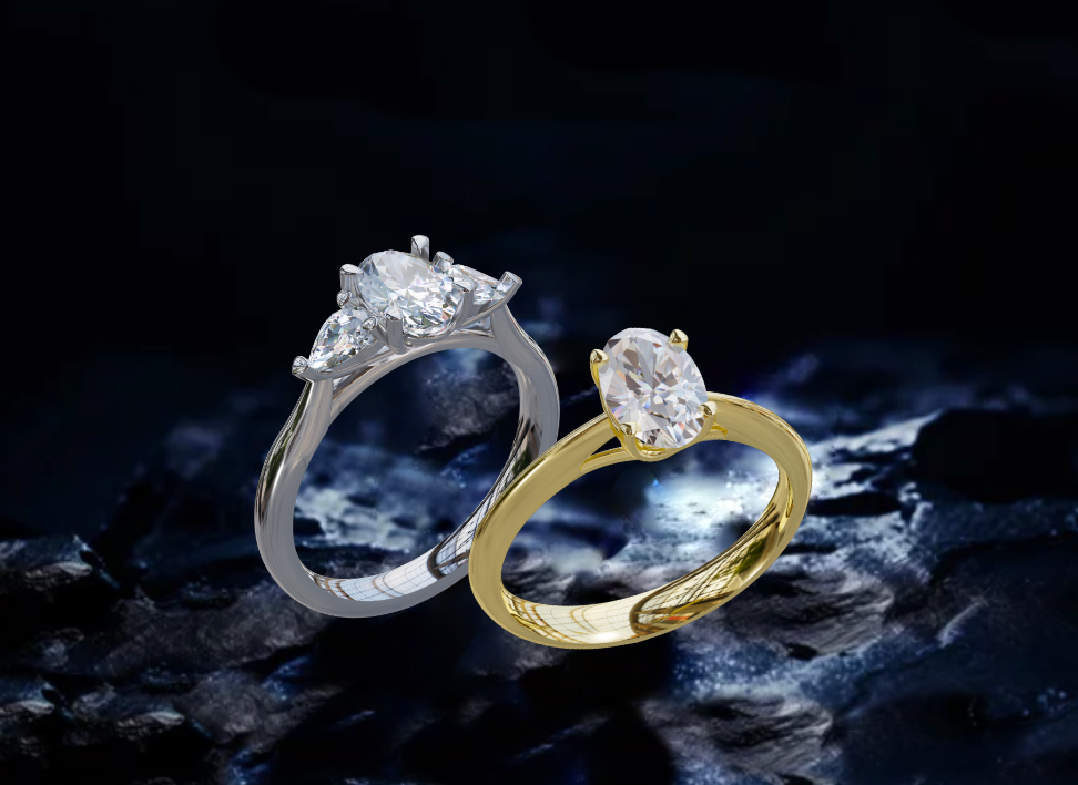 A lab-grown platinum three-stone engagement ring featuring pear and brilliant-cut diamonds, displayed alongside an 18ct yellow gold ring with an oval lab-grown diamond,