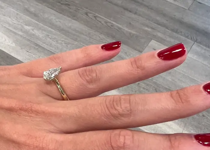 pear diamond engagement ring being worn on a finger